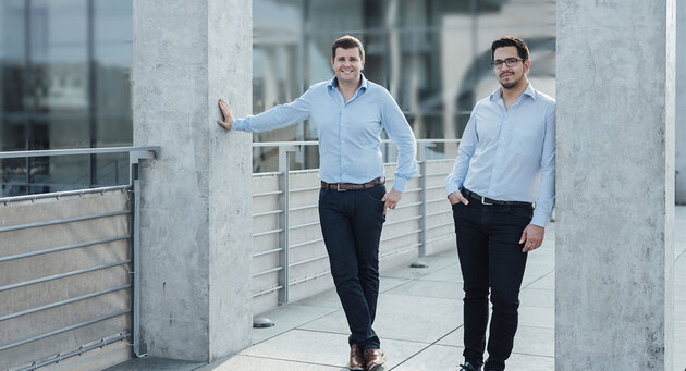 The two founders of brighter AI stand between two pillars two gray 