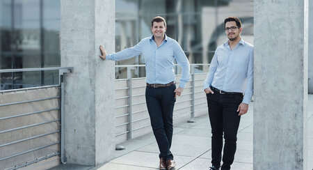 The two founders of brighter AI stand between two pillars two gray 